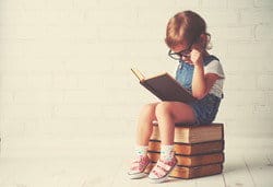 スペインで本の山の上に座って本を読む少女。 スペインで本の山の上に座って本を読む少女。