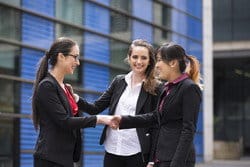 スペインの建物の前で握手をする 3 人の女性実業家。