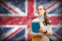 女の子がイギリスの国旗とスペインの前で本を持っています。 女の子がイギリスの国旗とスペインの前で本を持っています。