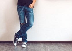 スペインの壁にもたれる、ジーンズとTシャツを着た男性。 スペインの壁にもたれる、ジーンズとTシャツを着た男性。