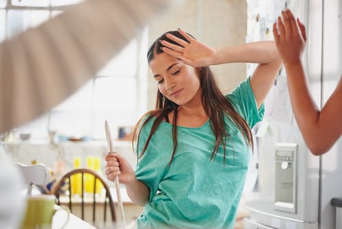 スペインで、別の女性がキッチンに立っている間、女性が頭を上げています。 スペインで、別の女性がキッチンに立っている間、女性が頭を上げています。