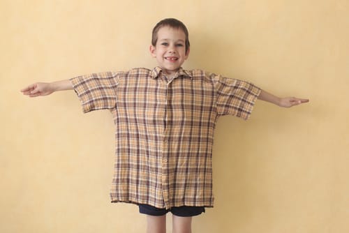 スペインの黄色い壁でポーズをとる格子縞のシャツを着た少年。