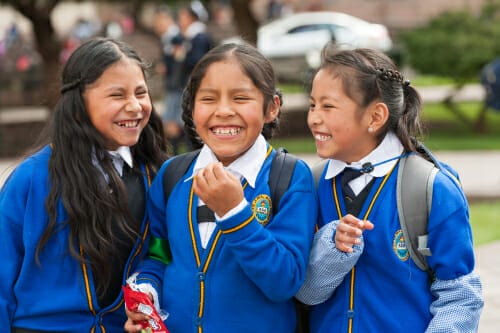 スペインで青い制服を着た3人の女の子が微笑んでいる。