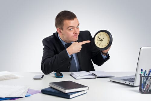 スペインにいるスーツを着た男性がラップトップの前で時計を持っています。 スペインにいるスーツを着た男性がラップトップの前で時計を持っています。