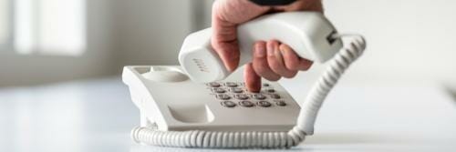 スペインのテーブルの上に白い電話を持っている人がいます。 スペインのテーブルの上に白い電話を持っている人がいます。