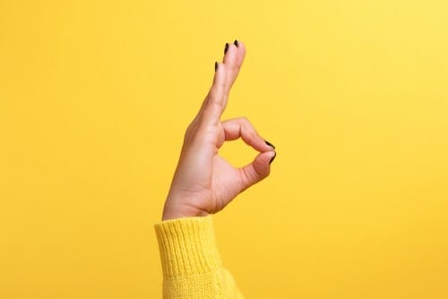 スペインの影響を受けた黄色の背景にOKサインを作る女性の手。 スペインの影響を受けた黄色の背景にOKサインを作る女性の手。