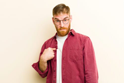 スペインで眼鏡をかけ、赤いシャツを着て指を指すひげを生やした男性。 スペインで眼鏡をかけ、赤いシャツを着て指を指すひげを生やした男性。